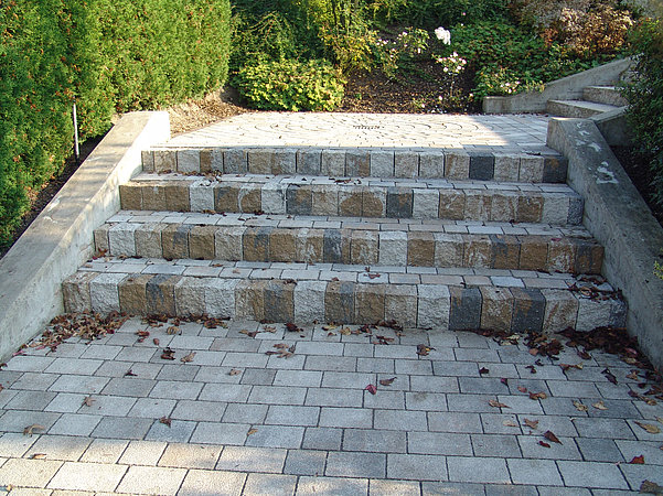 Concrete block steps with mixed-tone risers and coordinated paving stones in a landscaped garden path.
